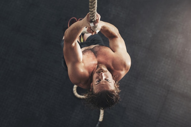 Beast mode comes naturally to me Shot of a muscular young man climbing a rope in a gym