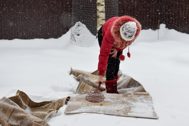 Batti il tappeto dalla polvere in inverno sulla neve. pulire i tappeti di casa con la neve. il tappeto giace sulla neve bianca