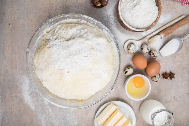 Sbattere la farina e gli utensili da cucina una teglia un mattarello con le uova sul tavolo concetto di cottura al forno chef che prepara pane e biscotti di pan di zenzero il cuoco impasta e arrotola la pasta