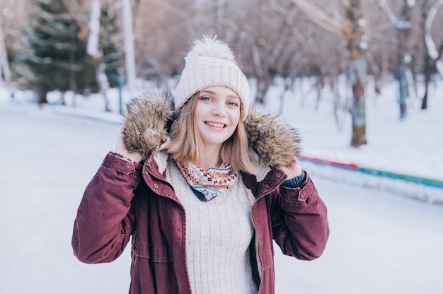 美しい女性の笑顔の肖像画。雪の冬の服を着て幸せな女の子の肖像画