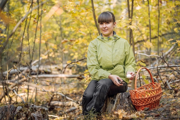 Beatiful girl picking mushrooms in the autumn forest