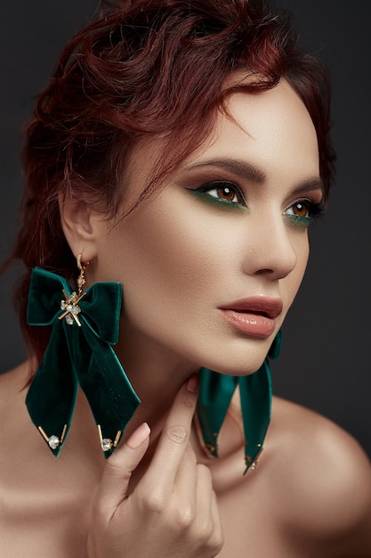 Beatiful red hair woman with make up and green earrings