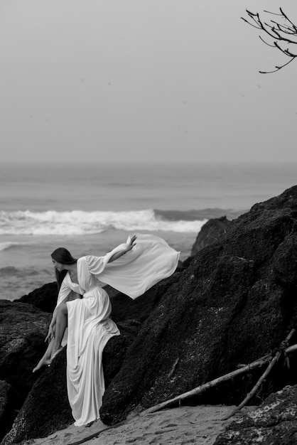 Beatifull young girl in wedding dress and on black beach in Varkala, Kerala with high rock