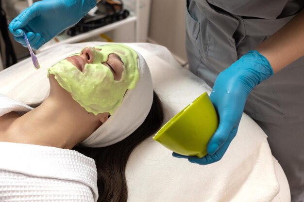 Photo beautician applies alginate mask on female face