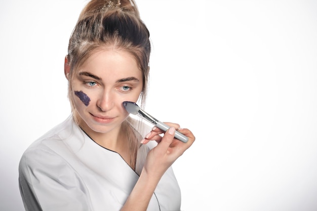 The beautician applies a cosmetic mask to clean the pores.