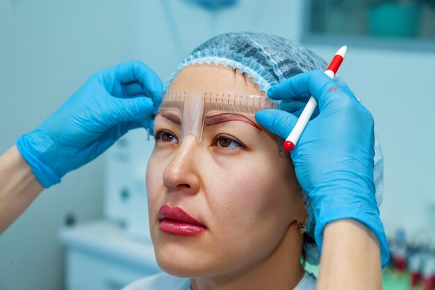 Beautician applies the markup on the eyebrows for permanent makeup eyebrows