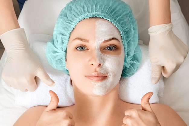 A beautician applies a mask to the face in a beauty salon