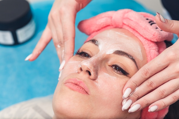 美容師は顔の皮膚に保湿剤を塗布します。