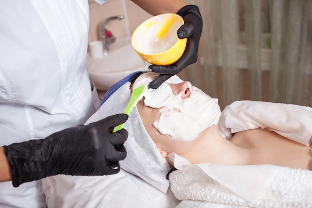 The beautician apply an alginite mask on client