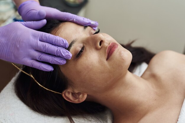 Beautician applying moisturizing cream on a client