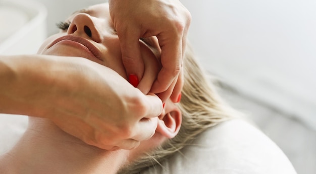 Il cosmetologo dell'estetista realizza la tecnica del pizzico e del rullo del massaggio facciale