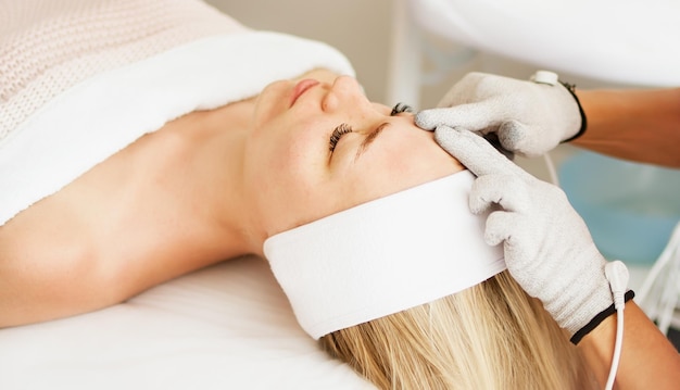 Il cosmetologo estetista esegue una procedura sul viso con guanti per terapia microcorrente. hardware.