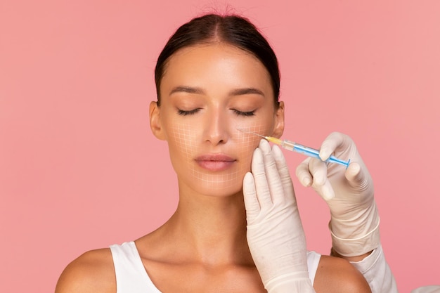 Photo beautician doctor making injection to beautiful woman with drawn mesh on face