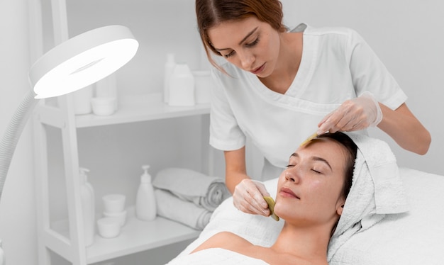 Photo beautician doing face beauty routine for female client