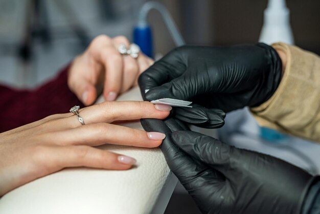 Beautician doing manicure female customer in nail salon Woman getting nail manicure