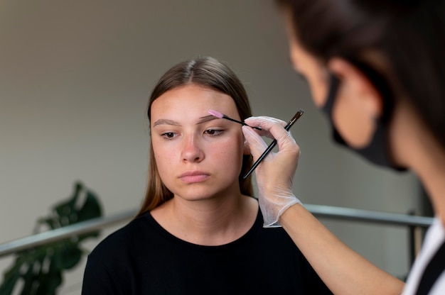 Foto estetista che esegue una procedura di microblading su una giovane donna