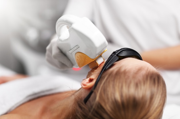 Beautician Giving Epilation Laser Treatment To Woman On Face