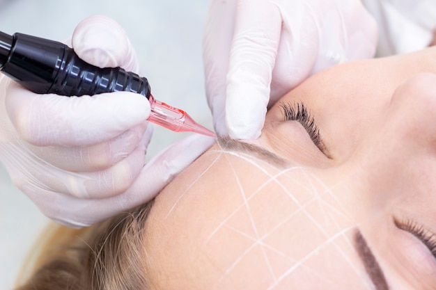 Beautician hands doing eyebrow tattoo