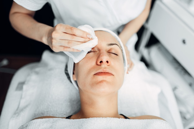 Beautician hands on female patient face, top view