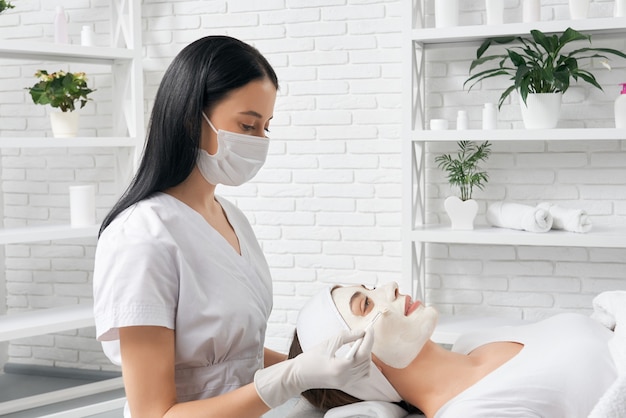 Beautician holding brush and doing procedure for woman