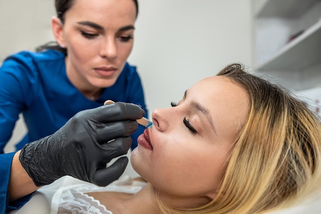 Косметолог удаляет волосы усы на губе женского клиента лицо воском горячий сахар в спа-салоне