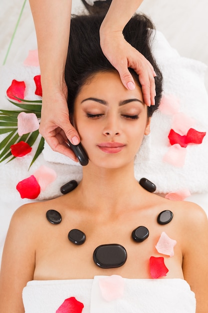 Beautician make stone massage spa for woman at wellness center