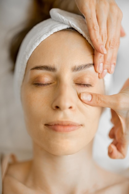 Beautician makes a face massage for a woman