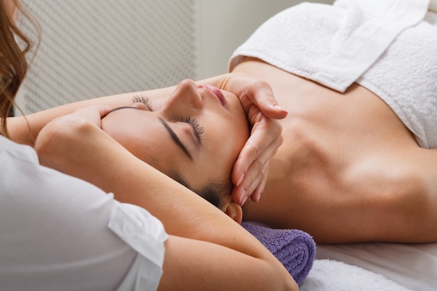 Beautician makes head massage in spa wellness center