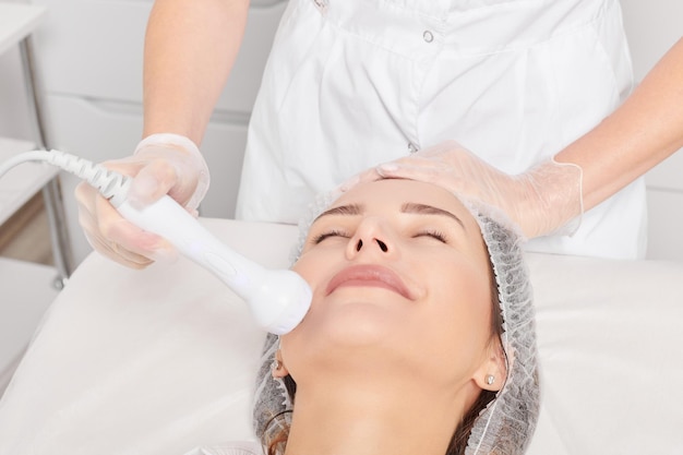 L'estetista esegue il sollevamento rf per il ringiovanimento del viso della donna procedura cosmetica antietà