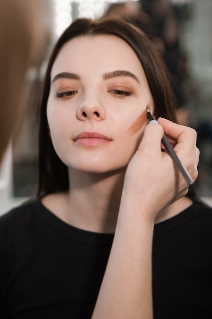 Beautician making face contouring with makeup brush