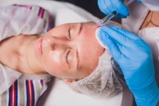 Beautician making injection in woman's face closeup Biorevitalization procedure