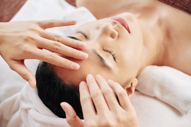 Foto estetista che massaggia la fronte dei clienti