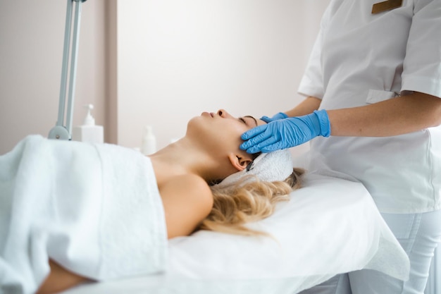 Beautician massaging the face of young girl in latex gloves