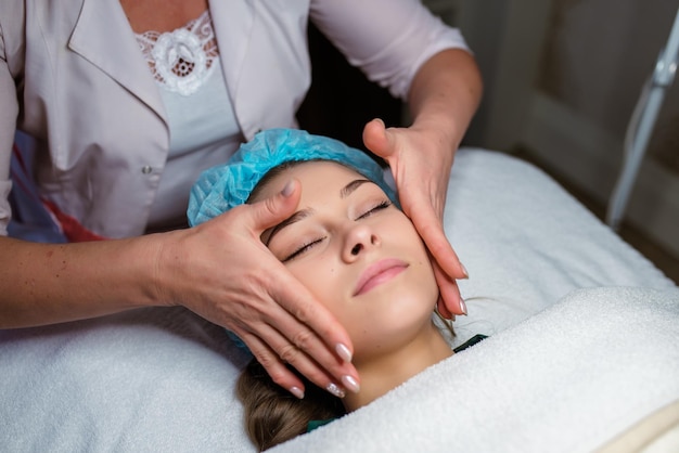 Beautician massaging woman's face Attractive girl having facial treatment and massage The young woman is lying and relaxingin