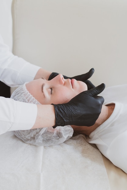 Beautician masseur doing facial massage to young woman