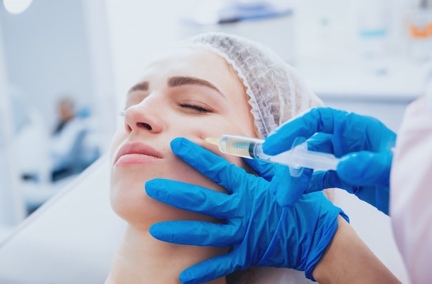 Beautician and the patient in the clinic of aesthetic medicine receiving a treatment