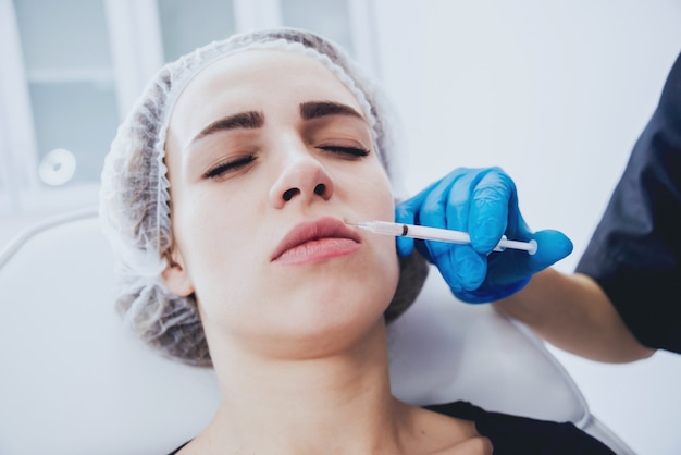 Beautician and the patient in the clinic of aesthetic medicine receiving a treatment