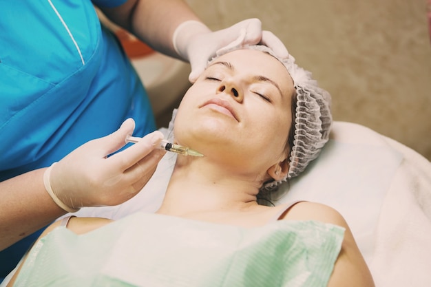 Beautician performs a needle mesotherapy treatment on a woman's face