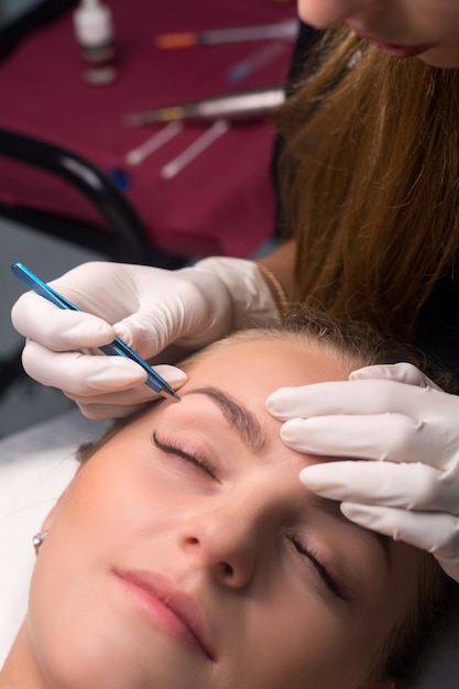 Beautician plucking eyebrows. eyebrow care in a beauty\
salon.