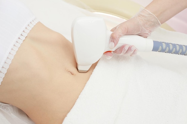 Beautician removes hair on a smooth female belly with a diode laser laser epilation closeup