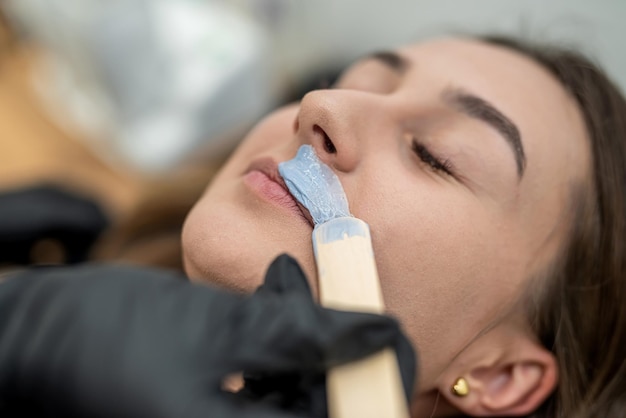 Beautician removes unwanted hair from a girl's upper lip the concept of depilation mustache