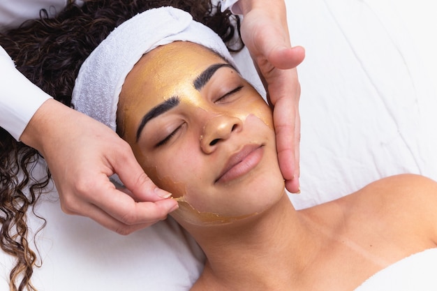 Beautician removing facial scrub mask