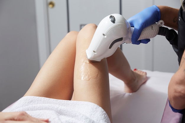 Beautician Removing Hair Of Young Woman' s leg with laser