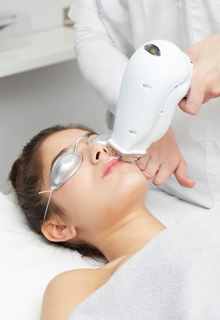 Photo beautician removing hair of young woman with laser