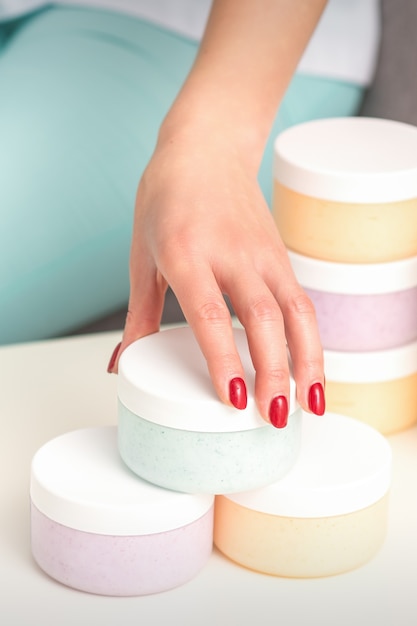 Beautician's hand takes jar with cosmetics from table offering and selling cosmetic products, moisturizing cream, wax paste.