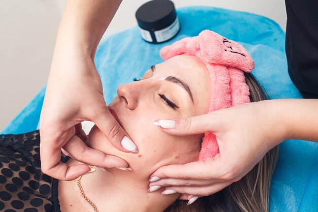 Beautician in the salon doing facial massage.