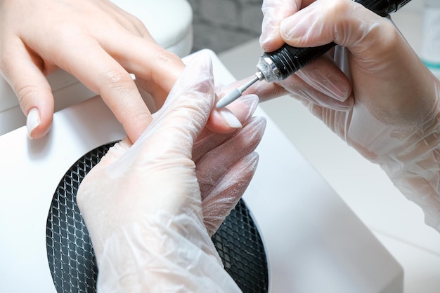 Beautician Salon, Manicure. Professional hardware manicure using electric machine in beauty salon. master uses an electric machine to remove nail polish hands during manicure