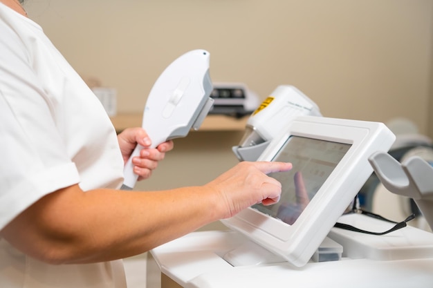 beautician tries to adjust screen settings of laser hair removal machine in private clinic