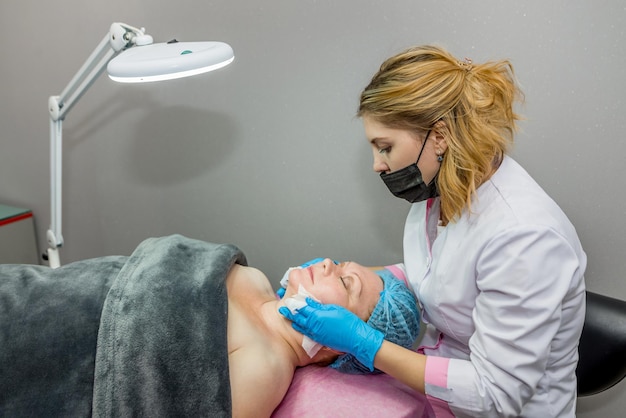 Beautician wipes the face of a client in a spa salon