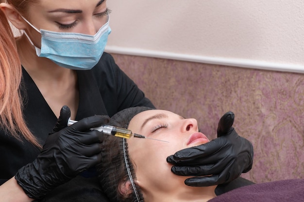 beautician with a syringe in the face of a patient in a spa salon